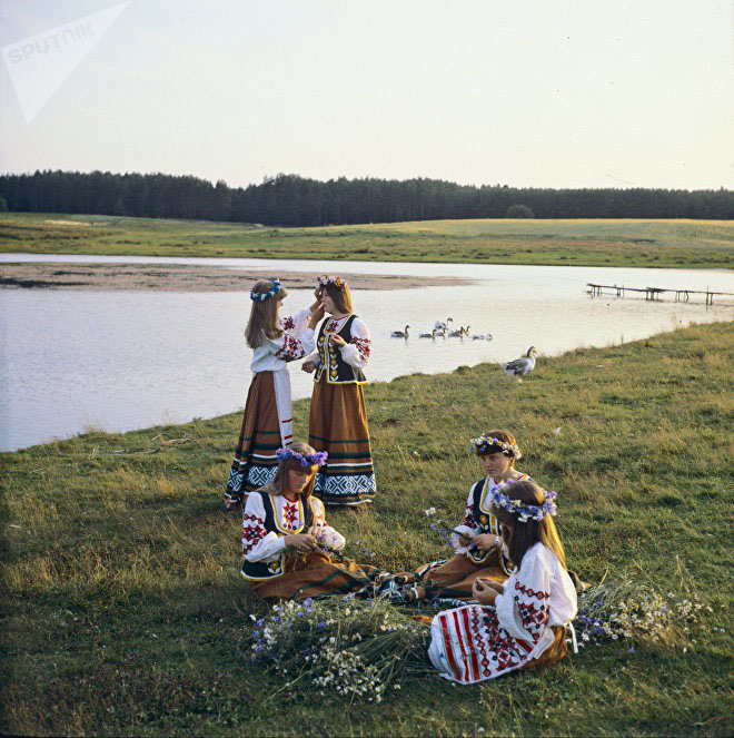 Девушки плетут венки у реки